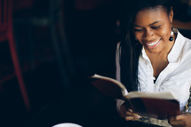 woman reading from a journal at a Bible study and smiling