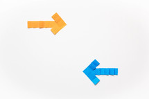A yellow paper arrow pointing right and a blue paper arrow pointing left on a white background.