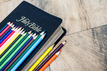 row of colored pencils on a Bible