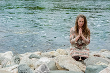 woman in prayer at a rocky shore