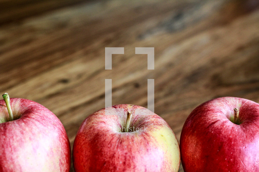 row of apples on wood background 