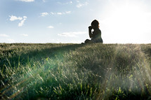 a child sitting in grass praying 
