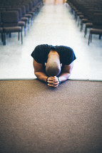 man kneeling in prayer at the altar of a church