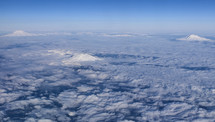 Aerial view of snow covered mountain peaks above the clouds