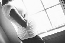 Pregnant woman standing in front of a window.