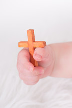 An infant's hand  clutching a wooden cross
