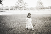 Girl walking in a field of grass outside.