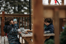 boys eating muffins on a back deck 