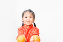 a little Asian girl holding oranges 