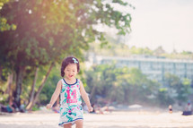 Little Asian girl playing on the beach.