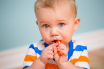 an infant boy eating a lollipop 