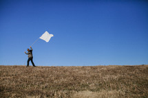 business man in a field holding a white flag - surrendering