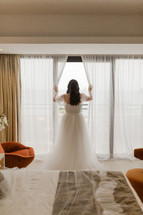 Bride looking out a window on her wedding day.