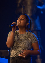 young woman with a microphone singing on stage 