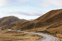 A highway winding through brown hills.