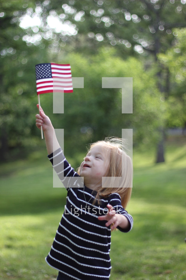 Girl standing outside holding and American flag.