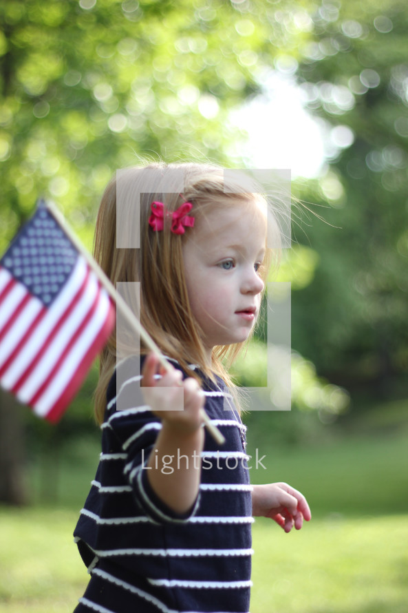 Girl standing outside holding and American flag.