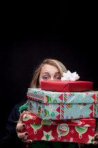 a woman holding a stack of Christmas presents 
