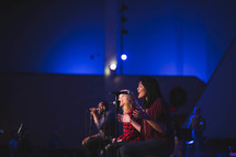 musicians singing into microphones during a worship service