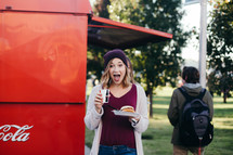 a woman getting food and drink from a food truck 