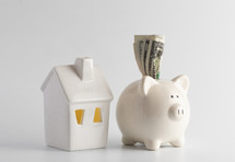 small white house and piggy bank against a white background 