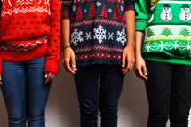 friends standing in ugly Christmas sweaters 