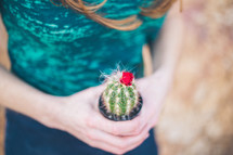 a woman holding a potted cactus 