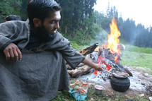 man cooking in a pot on an open fire 