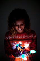 a woman holding glowing Christmas lights 