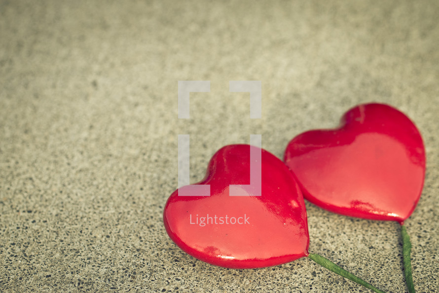 Solid Red Hearts with Green Stems on a textured background