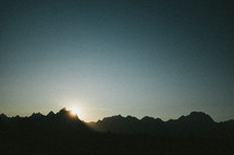 sunrise behind mountain peaks 