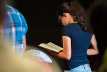 a teen girl holding a Bible during a worship service 