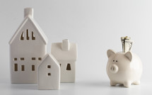 piggy bank and small white house against a white background 