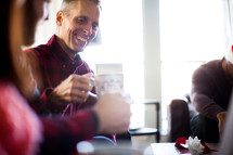 A man smiling and drinking coffee at a Christmas party