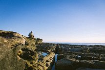 woman sitting on a rocky beach 