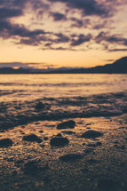 stones on wet sand at sunset 