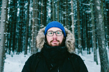 man in a coat standing in a winter forest 