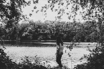a woman standing on the edge of a pond 