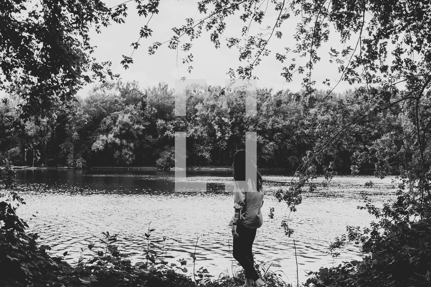 a woman standing on the edge of a pond 