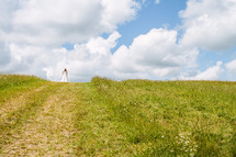 bride standing at the top of a grassy hill 