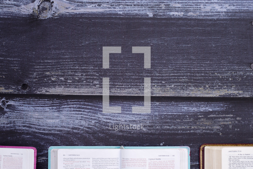 edges of open Bibles on wood background 