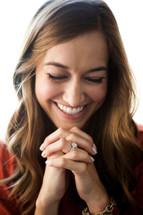 A smiling young woman with her hands clasped in prayer.