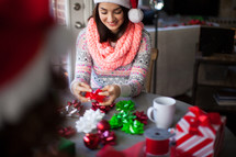 A young woman in a santa hat wrapping Christmas presents
