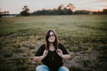 a woman squatting in a field at sunset 