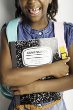a girl child holding a composition notebook 
