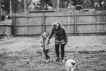 Mom and daughter playing with a dog in the yard