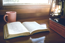open bible for morning devotion on wooden table with sunlight