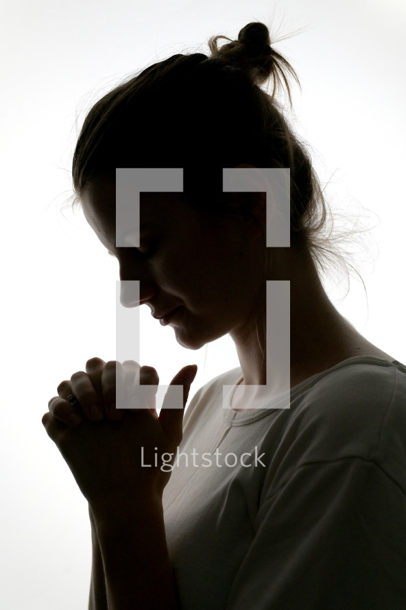 Closeup Profile Of A Woman Praying In Silhouette Isolated in Studio