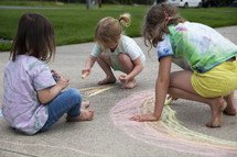 children drawing a rainbow with sidewalk chalk 