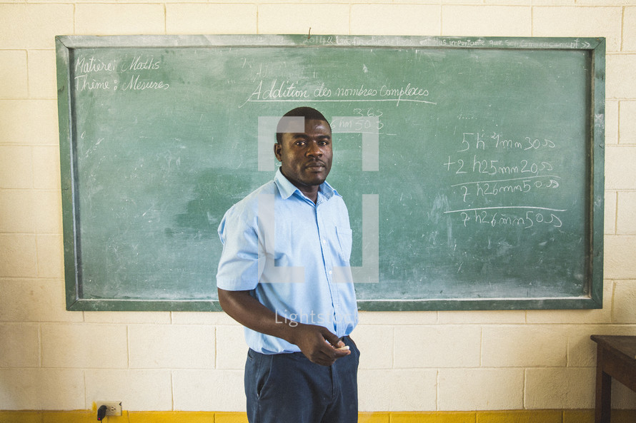 Teacher in front of a chalkboard in a classroom.